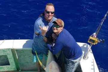 a man holding a fish on a boat