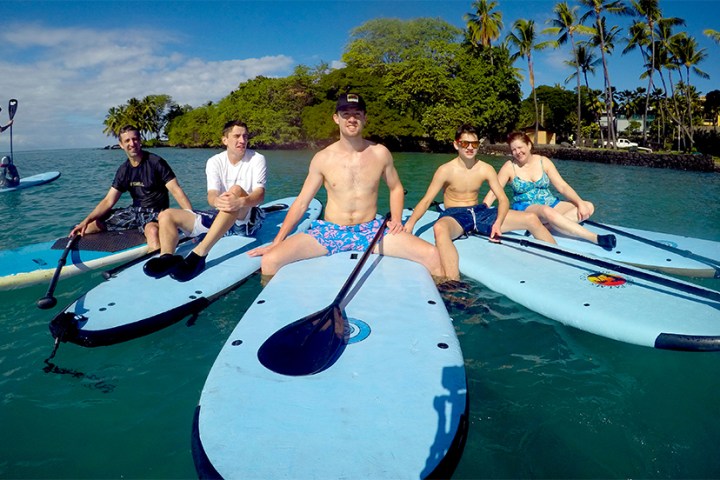 a group of people riding on the back of a boat in the water