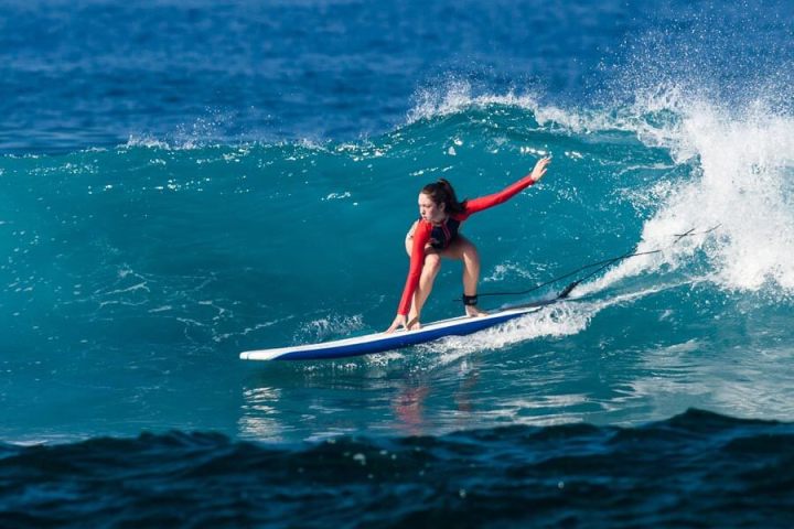 a young girl riding a wave on a surfboard in the ocean