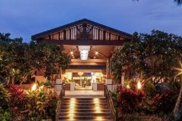 a sign in front of a palm tree