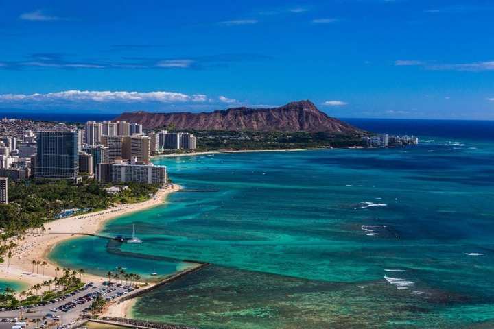 a view of a beach next to a body of water with Diamond Head in the background