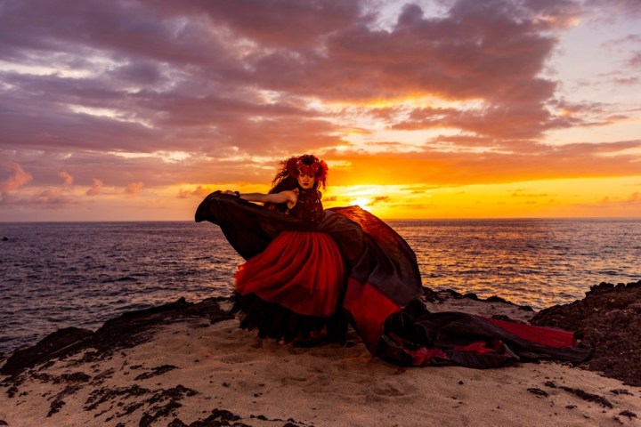 a person sitting on a beach with a sunset in the background