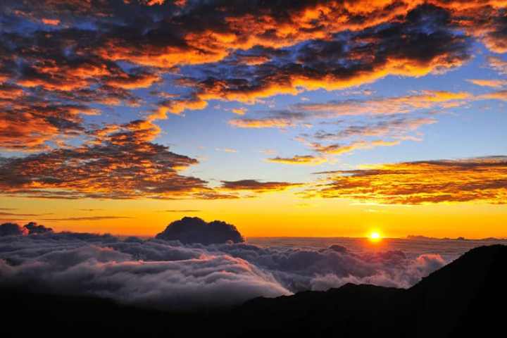 a sunset over a body of water with a mountain in the background