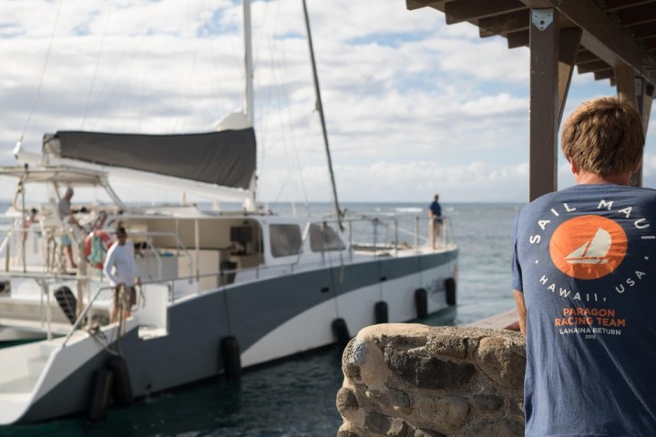 a man standing in front of a boat next to a body of water