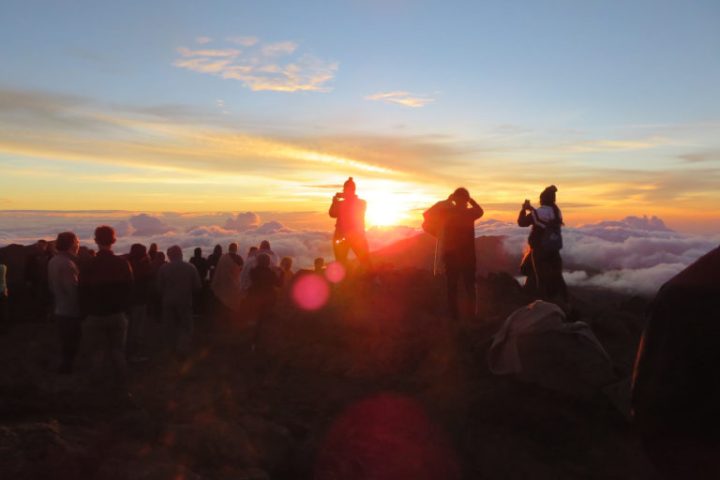 a group of people standing in front of a sunset