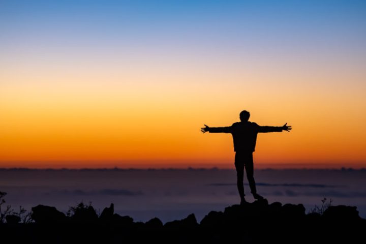 a man standing in front of a sunset