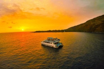 a small boat in a large body of water at sunset