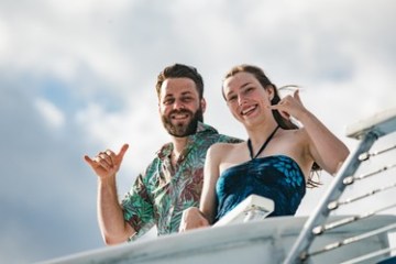 a woman and man standing in front of a boat