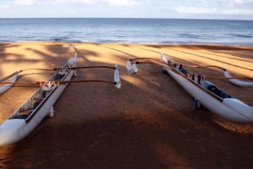 a row of wooden canoes sitting on top of a sandy beach