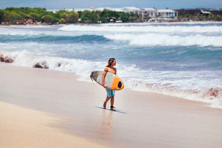 a man carrying a surf board walking on a beach