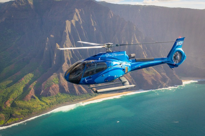 a helicopter flying over a body of water with a mountain in the background
