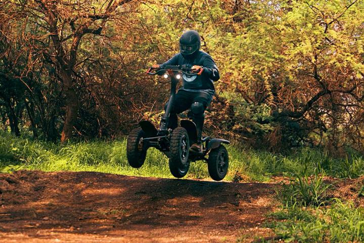 a man riding a atv down a dirt road