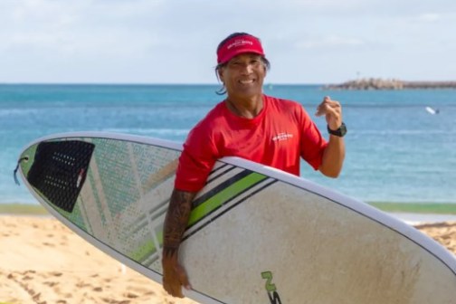 a man carrying a surf board on a body of water