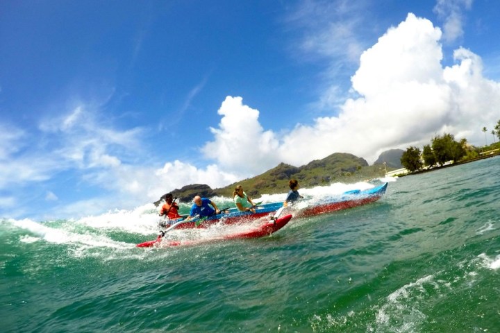 a group of people riding on top of a wave in the ocean