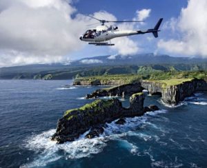 doors-off-maui-1024×834 (1) Helicopter flying over rugged coastline with ocean and cliffs in the background.