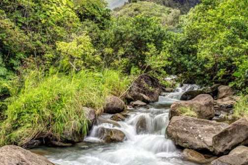a large waterfall over some water in iao valley