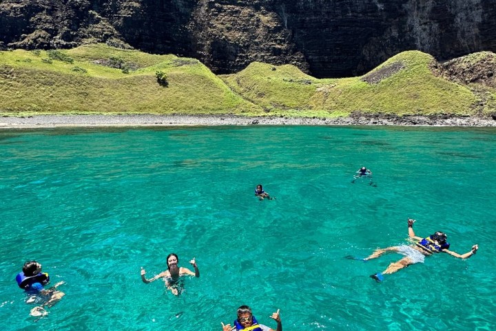 a group of people swimming on the na pali coast