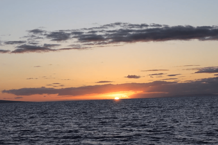 Sunset over ocean with clouds spread across the sky.