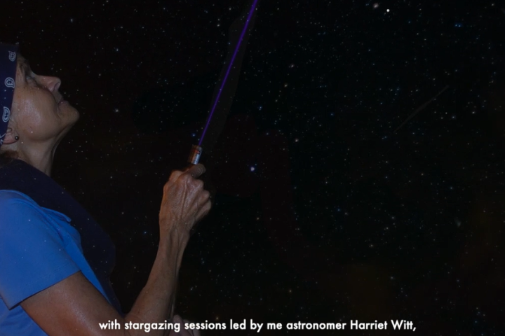 Person pointing a flashlight at the starry night sky.