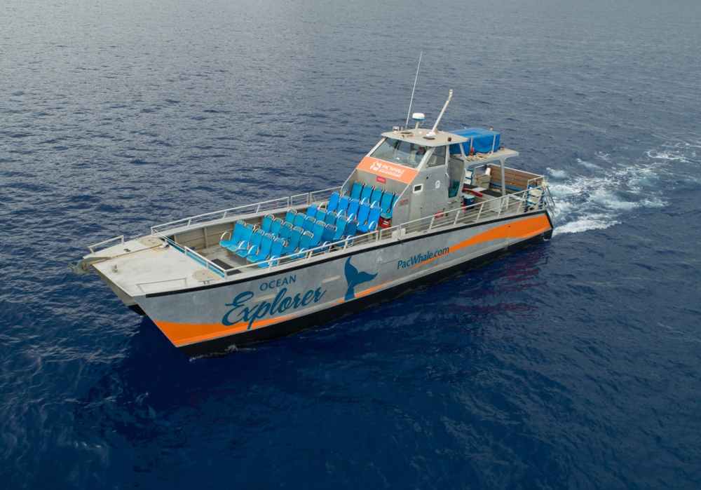 Boat named Ocean Explorer in open water, with empty blue seats on deck.
