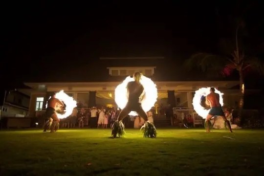 People performing fire dance at night in front of a building.