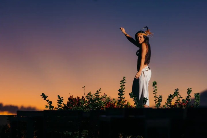 Person dancing outdoors at sunset, wearing traditional attire.