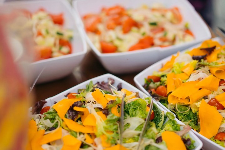 Various salads with vegetables and cheese in white bowls on a table.