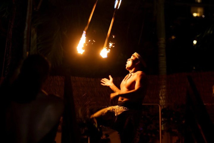 Performer juggles flaming torches at night.
