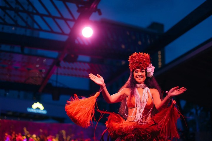 Woman in red traditional dress dancing under pink light.